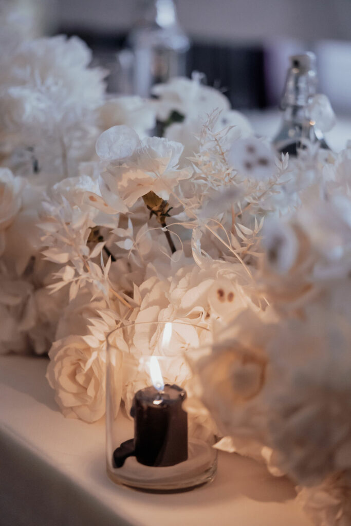 Brauttisch mit weißen Blumen und schwarzer Kerze
